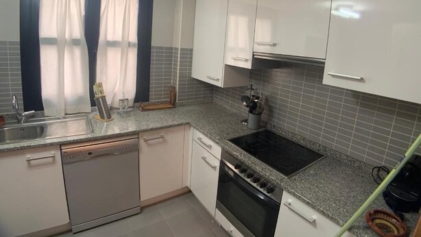 A kitchen with white cabinets, a dishwasher, an oven, and a stove.
