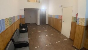 A hallway with a row of seating, a door, and a tiled wall.