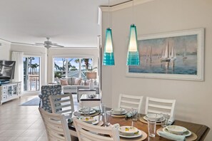 A dining area with a table set for four, chairs, and a painting of sailboats on the wall.