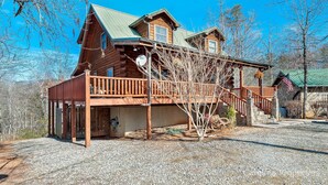 A log cabin with a wooden deck and a stone staircase leading to the entrance. - Hot Tub, Mirror Lake Access, Fireplace - Outlander Cabin by Carolina Properties (Lake Lure)