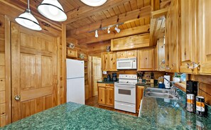Une cuisine avec des meubles de rangement en bois, un réfrigérateur blanc, une cuisinière et un four à micro-ondes.
