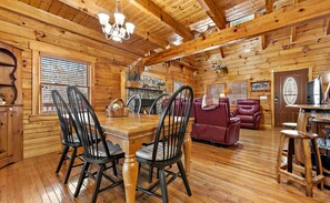 L’intérieur d’un chalet en bois comprend une table à manger, des chaises, un canapé et une cheminée.