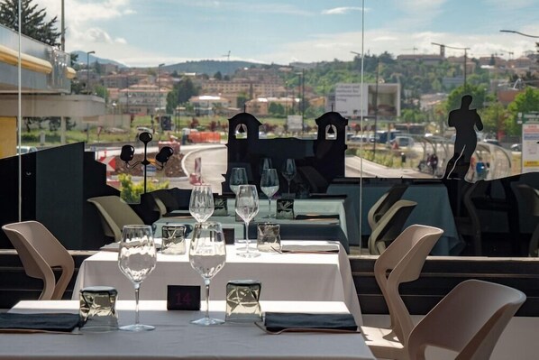 A restaurant table set with wine glasses and a digital clock displaying 14. - Hotel Amiternum (L'Aquila)