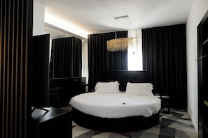 A modern hotel room with a large bed, a desk, and a hanging light fixture. - Hotel Amiternum (L'Aquila)