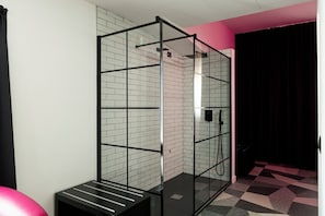 A modern bathroom with a glass shower enclosure, white brick walls, and a checkered floor. - Hotel Amiternum (L'Aquila)