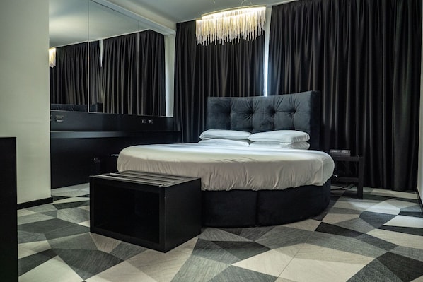 Un dormitorio moderno con una cama grande, una mesita de noche, un aparador y un espejo.