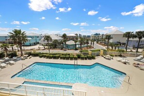 A swimming pool with lounge chairs and palm trees, surrounded by buildings. - Indies 101 | Modern Corner Beach Condo | Spacious Balcony Retreat (Gulf Shores)