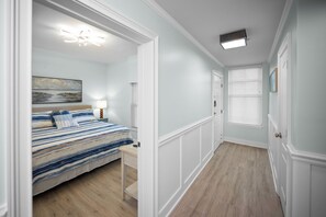 A bedroom with a bed, bedside table, lamp, and a painting on the wall. - Indies 101 | Modern Corner Beach Condo | Spacious Balcony Retreat (Gulf Shores)