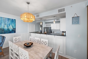 A modern kitchen with white cabinetry, a central island, and pendant lighting. - Indies 101 | Modern Corner Beach Condo | Spacious Balcony Retreat (Gulf Shores)