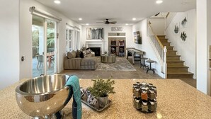 A spacious living area with a fireplace, a pool table, and a staircase leading to a second floor. - The Lakefront Social: An Extraordinary Waterfront Experience (Indio)