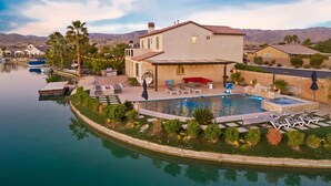 A house with a swimming pool, lounge chairs, and a patio area. - The Lakefront Social: An Extraordinary Waterfront Experience (Indio)