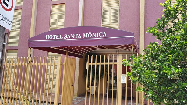 La entrada del HOTEL SANTA MÔNICA, con un acceso cubierto y un camino de entrada portón cerrado.