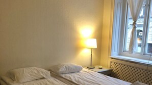 A single bed with a headboard, a bedside table with a lamp, and a window with sheer curtains. - Stockholm Central Apartment 911 (Stockholm)