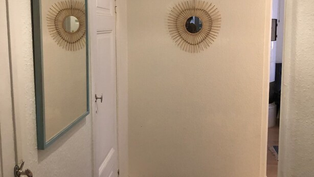 A hallway with a door, a mirror, and a wall-mounted light fixture. - Stockholm Central Apartment 911 (Stockholm)