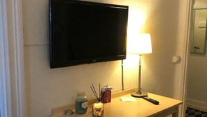 A small, well-lit room with a flat-screen TV mounted on the wall, a desk with a lamp, a chair, and a small decorative item on the desk. - Stockholm Central Apartment 911 (Stockholm)