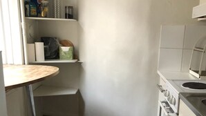 A compact kitchen with white cabinets, a stove, and a sink. There is a small countertop and a tiled floor. - Stockholm Central Apartment 911 (Stockholm)