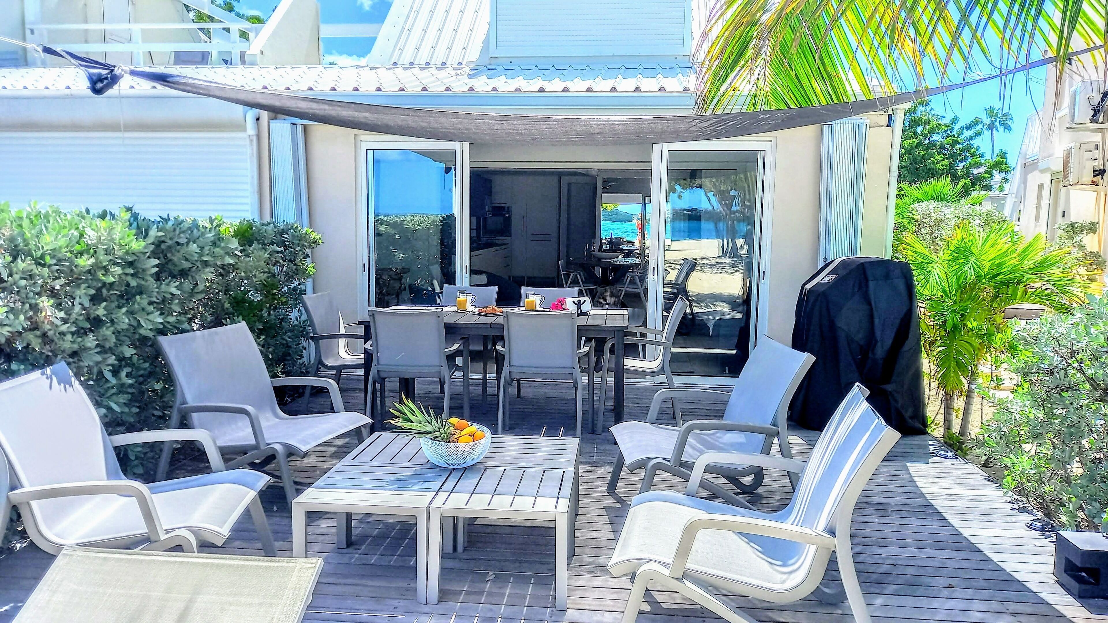 Eine Terrasse im Freien mit Tisch, Stühlen, einem Grill und Blick auf das Meer.