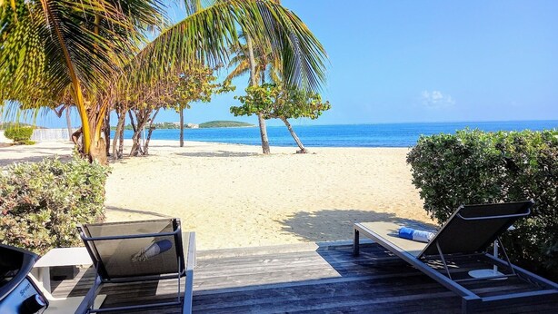 Une vue sur la plage, avec des chaises longues et une terrasse en bois.