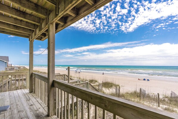 A wooden deck overlooking a beach with a clear sky.