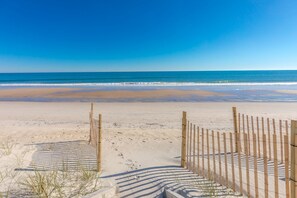 Ein Strand mit einer Holzlattenveranda und freiem Blick auf den Ozean.