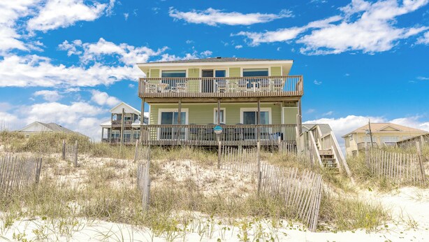 A two-story beachfront house with a balcony, surrounded by sand dunes and sparse vegetation. - Sanderling - 4 bedroom, 2.5 Oceanfront Home in North Topsail Beach! (North Topsail Beach)