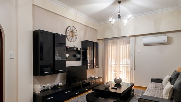 A modern living room with a flat-screen TV, black entertainment unit, and a sofa. - 2br renovated flat close to metro (Athens)