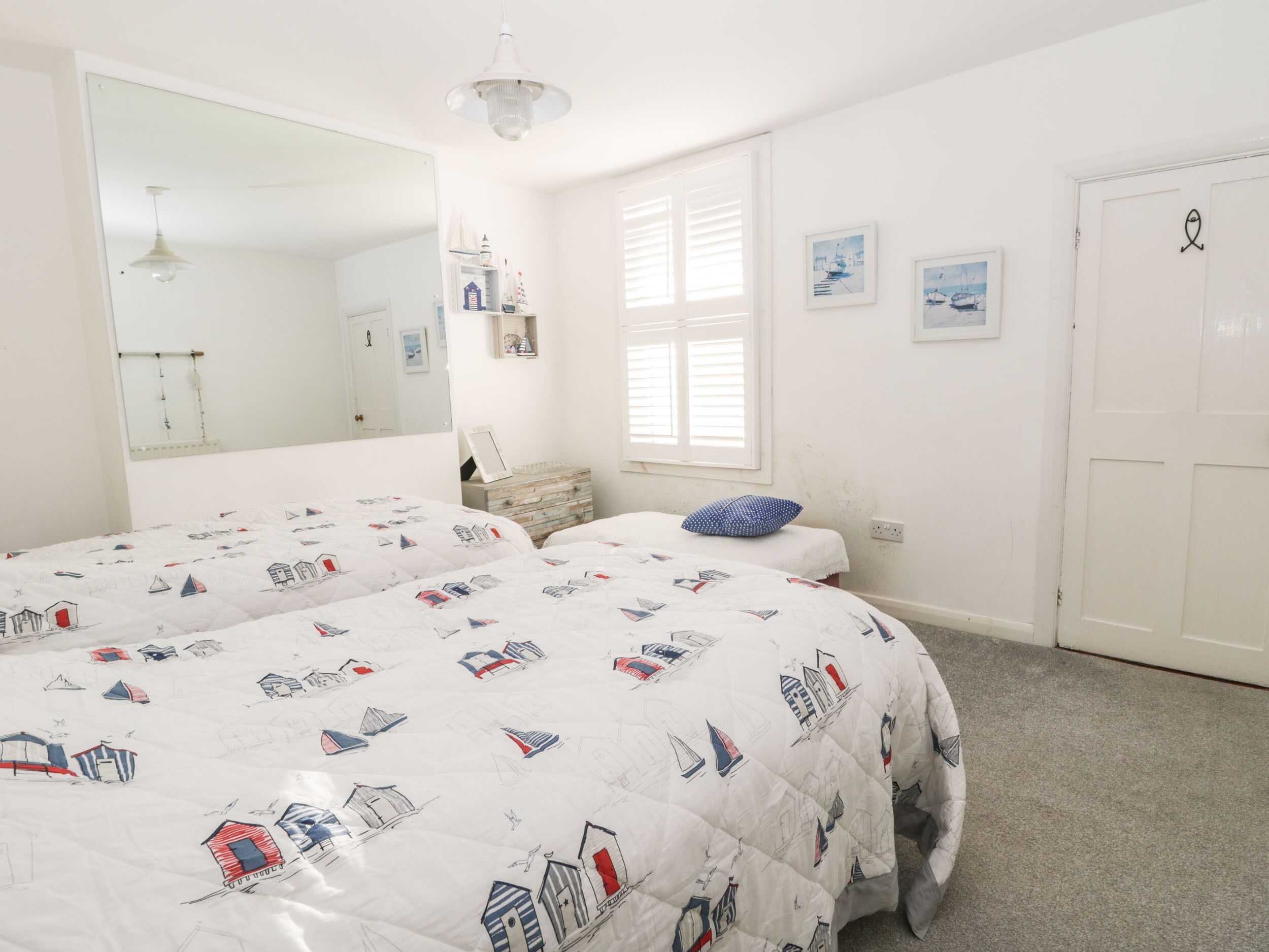 Une chambre avec deux lits, un grand miroir et une fenêtre avec des stores.