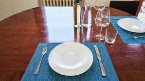 A wooden dining table with a white plate, fork, and knife set on a blue placemat. - Casa Ambra tranquility in the city center ⭐️⭐️⭐️⭐️⭐️ (Padova)