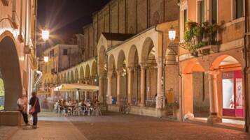 Une rue historique bordée d’arcades, dotée d’une terrasse et d’un trottoir pavé.