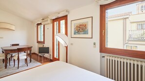 A room with a dining table, chairs, a TV, a lamp, a framed picture, and a window with a view of buildings. - Casa Ambra tranquility in the city center ⭐️⭐️⭐️⭐️⭐️ (Padova)