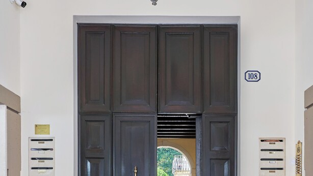 A hallway with a large wooden door, a security camera, and a number sign. - Casa Ambra tranquility in the city center ⭐️⭐️⭐️⭐️⭐️ (Padova)