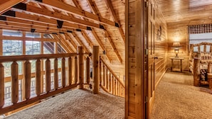 Un interno in legno con soffitto alto, una scala e vista attraverso ampie finestre.