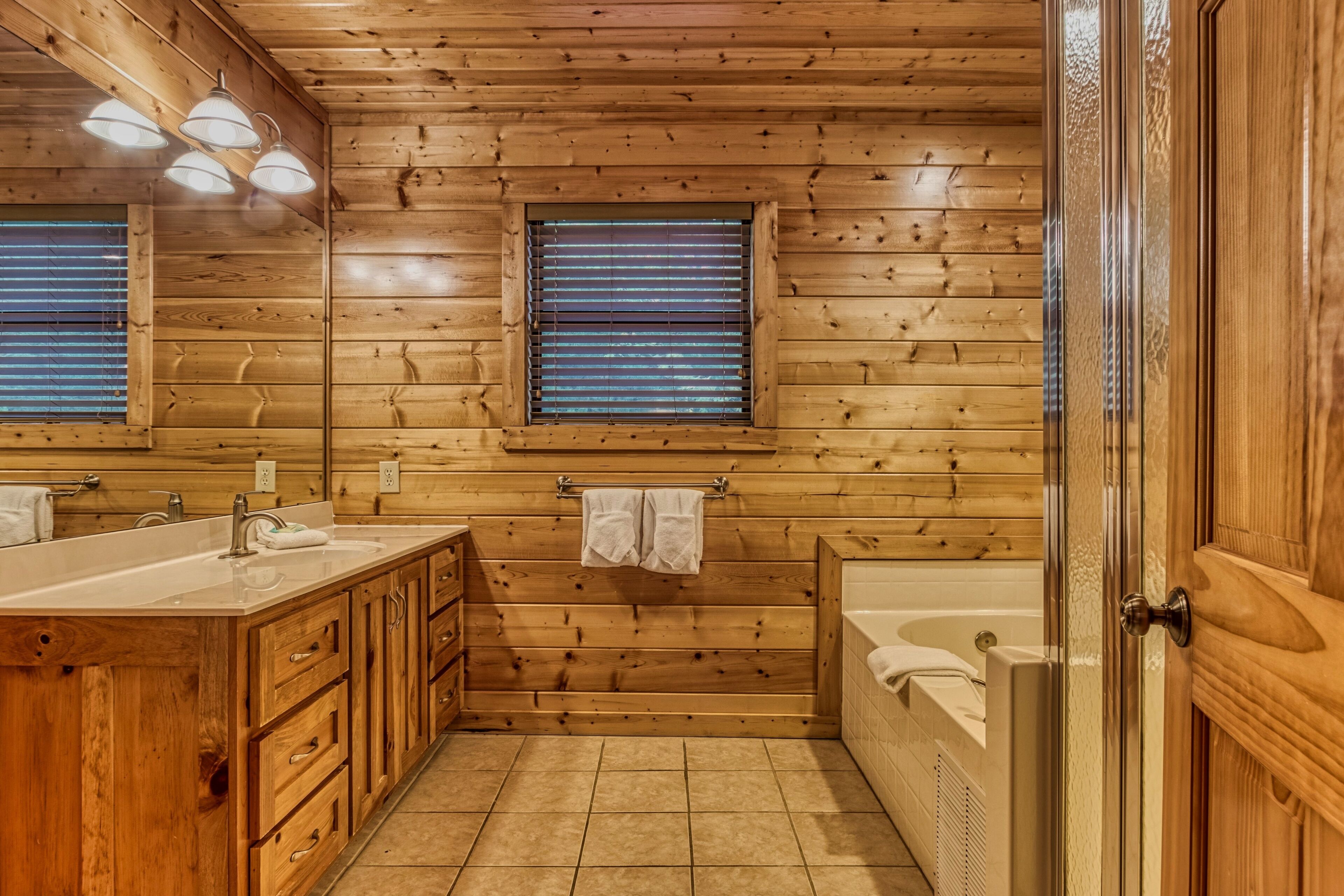 Une salle de bain de style rustique, avec des murs en bois, un grand meuble-lavabo, une baignoire et une douche.