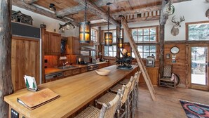 Una cocina rústica con vigas de madera, una larga mesa de madera y una chimenea.