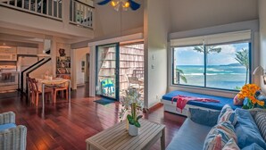 A spacious living area with a view of the ocean, a dining area, and a kitchen. - Oceanfront views all the way to the lighthouse! (Princeville)