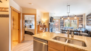 A modern kitchen with granite countertops, stainless steel appliances, and a large sink. - Steps away from Super Bee Lift, wifi, underground parking (Copper Mountain)