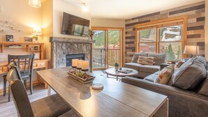 A modern living room with a fireplace, a dining area, and a sofa. - Steps away from Super Bee Lift, wifi, underground parking (Copper Mountain)