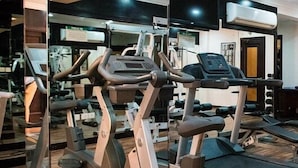 A gym with exercise equipment, a mirrored wall, and a treadmill. - Garden Hotel Muscat (Muscat)