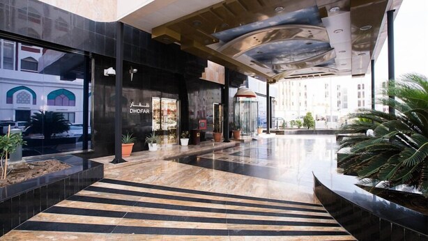 A modern hotel lobby with a black and beige striped floor, a glass entrance, and a view of the cityscape. - Garden Hotel Muscat (Muscat)
