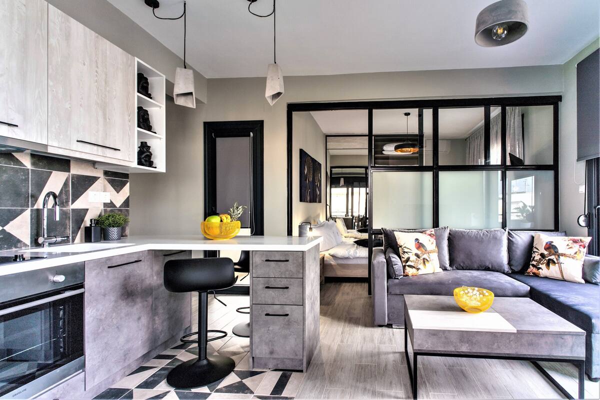 A modern kitchen with a central island, bar stools, and a built-in oven.