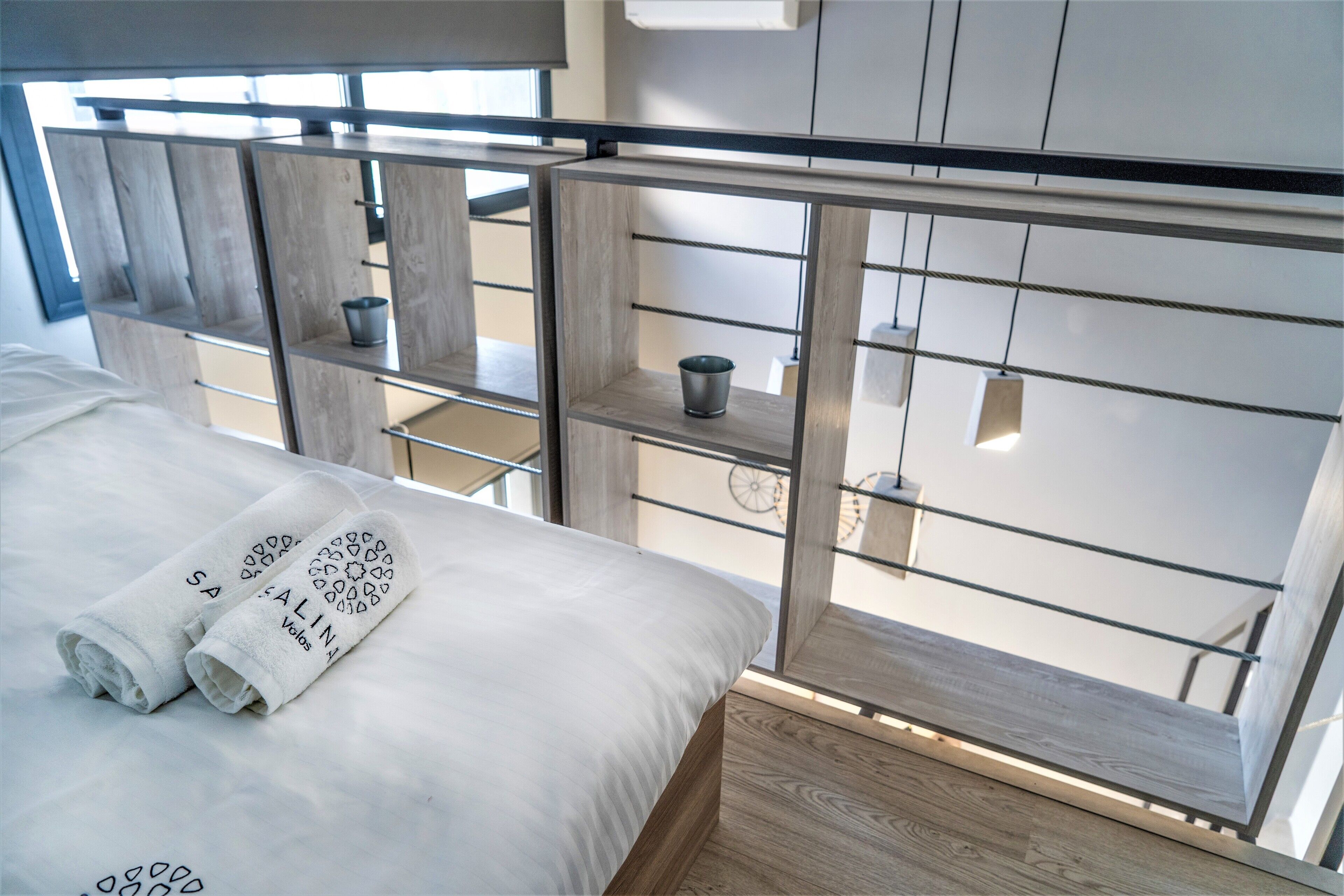 A modern hotel room with a bed, a wooden floor, and a balcony with a view.