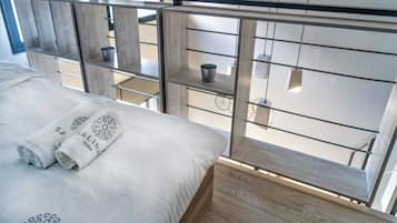 A modern hotel room with a bed, a wooden floor, and a balcony with a view.