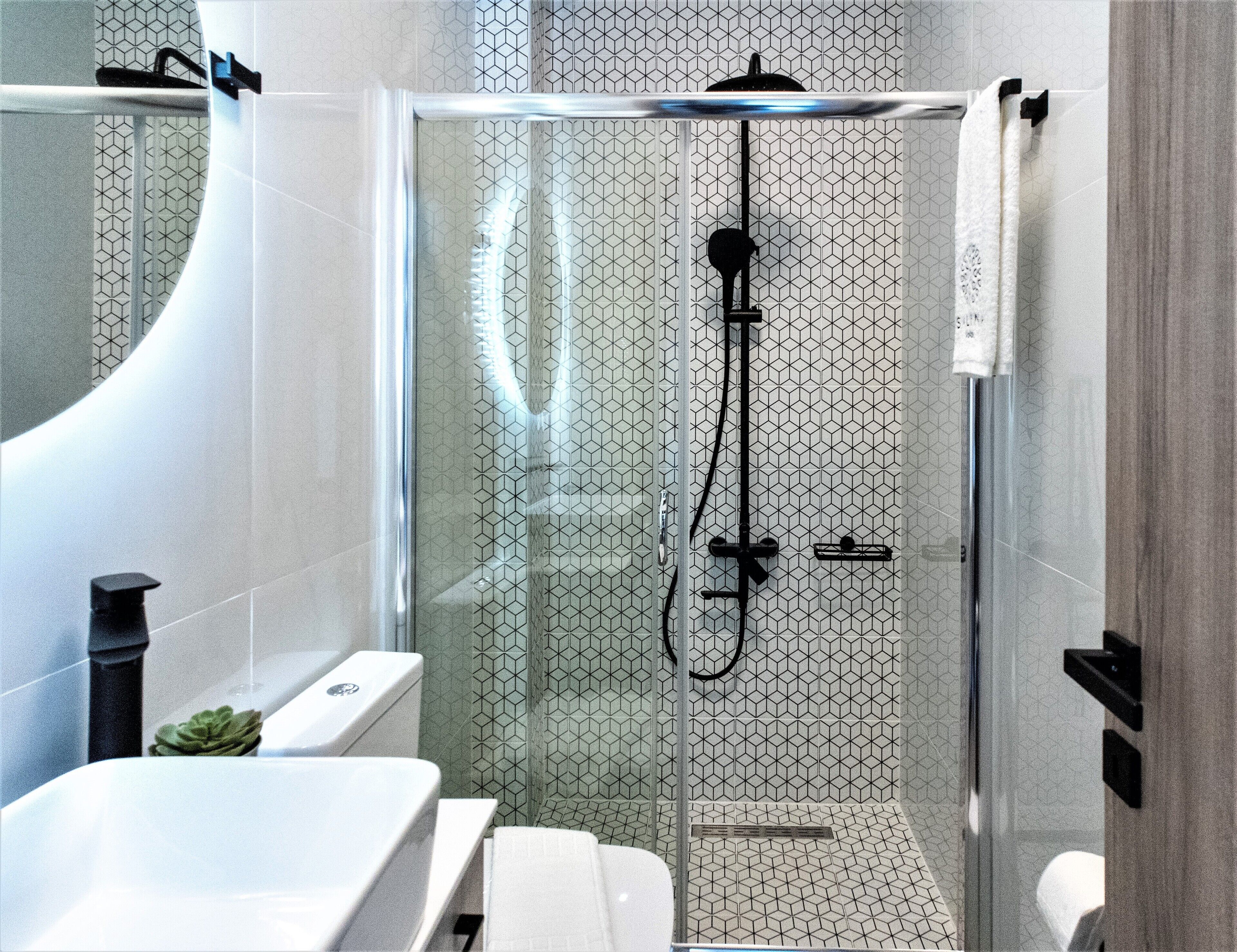 Ein modernes Badezimmer mit einer Duschkabine, einem weißen Waschbecken und einer Toilette.