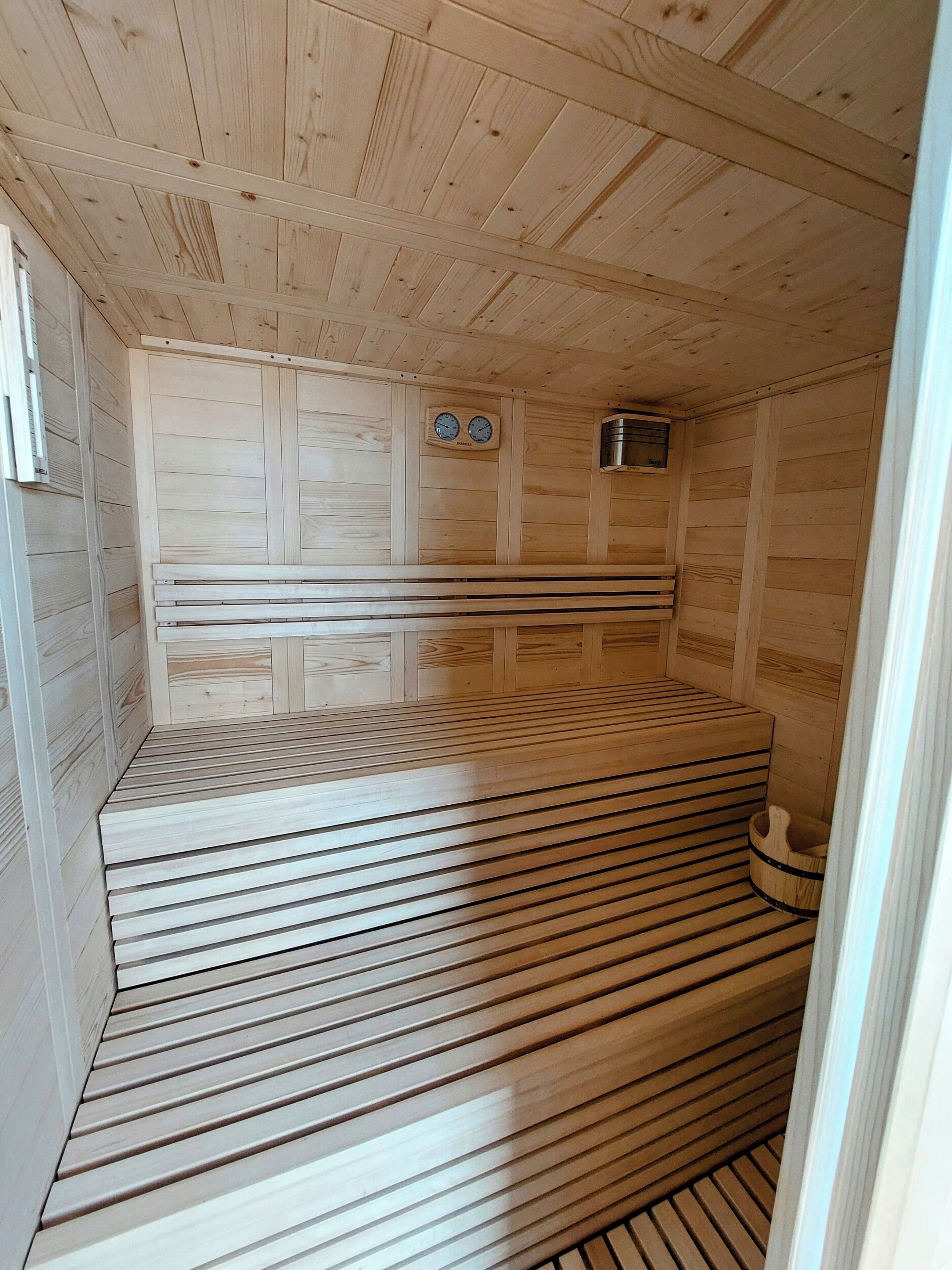 A sauna with wooden slatted floors and walls, a bench, and a small heater.