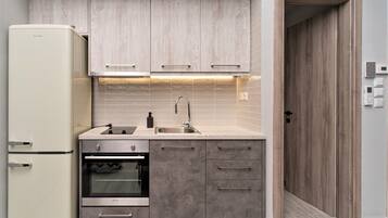 Una cocina compacta equipada con refrigerador, horno, pileta y gabinetes de madera.