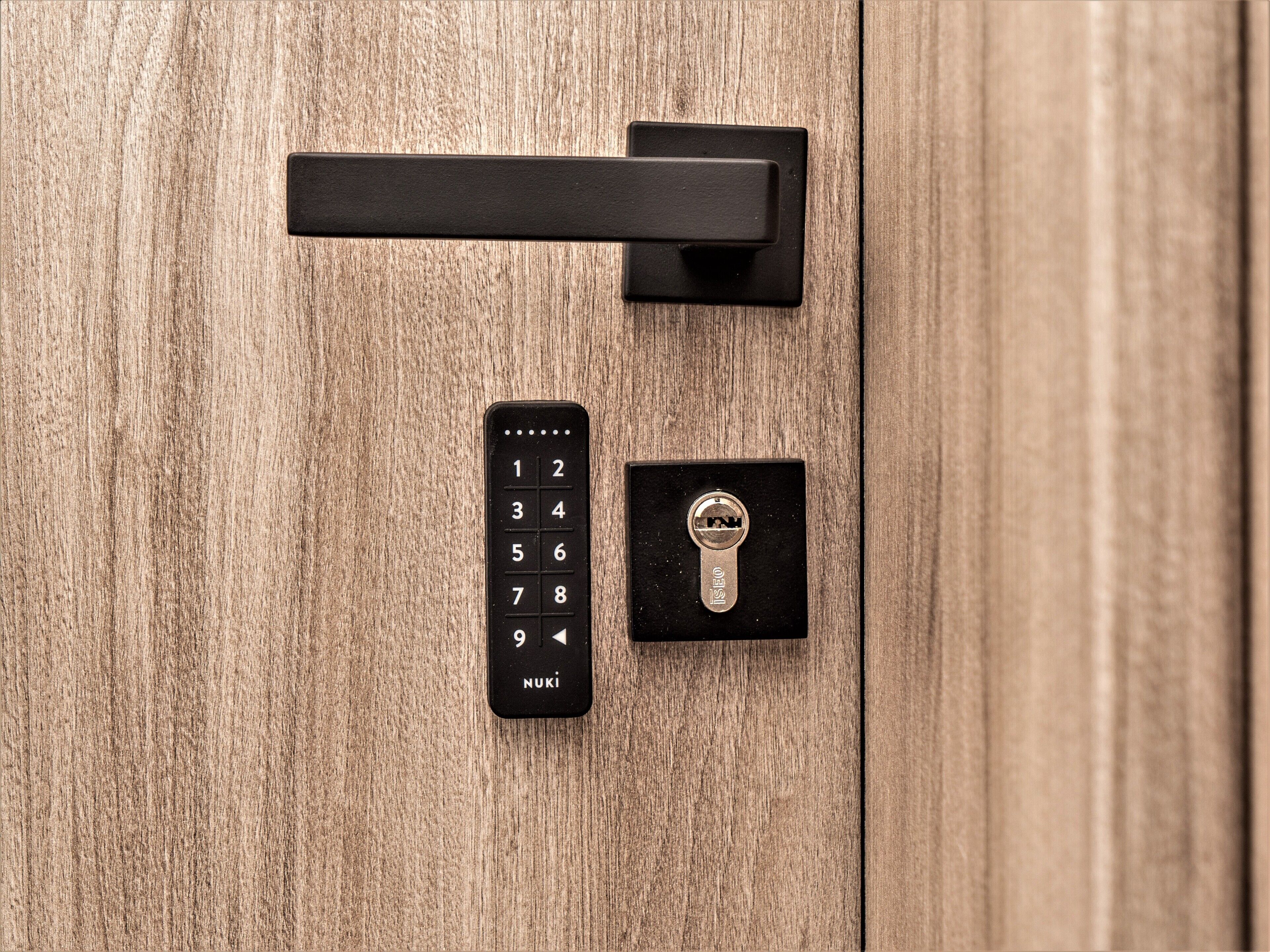 A wooden door with a black numeric keypad and a keyhole.