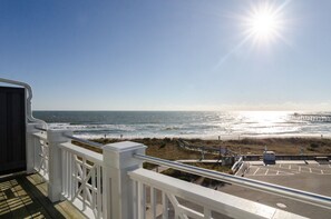 A beach view from a balcony with a clear sky and sun shining.
