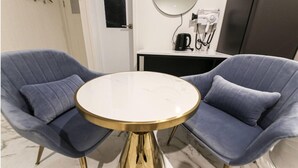Una habitación con dos sillones azules y una mesa redonda con base dorada.