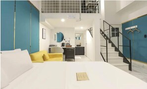 A modern hotel room with a bed, a yellow armchair, a kitchenette, and a staircase. - Hotel Arentz (Anyang)