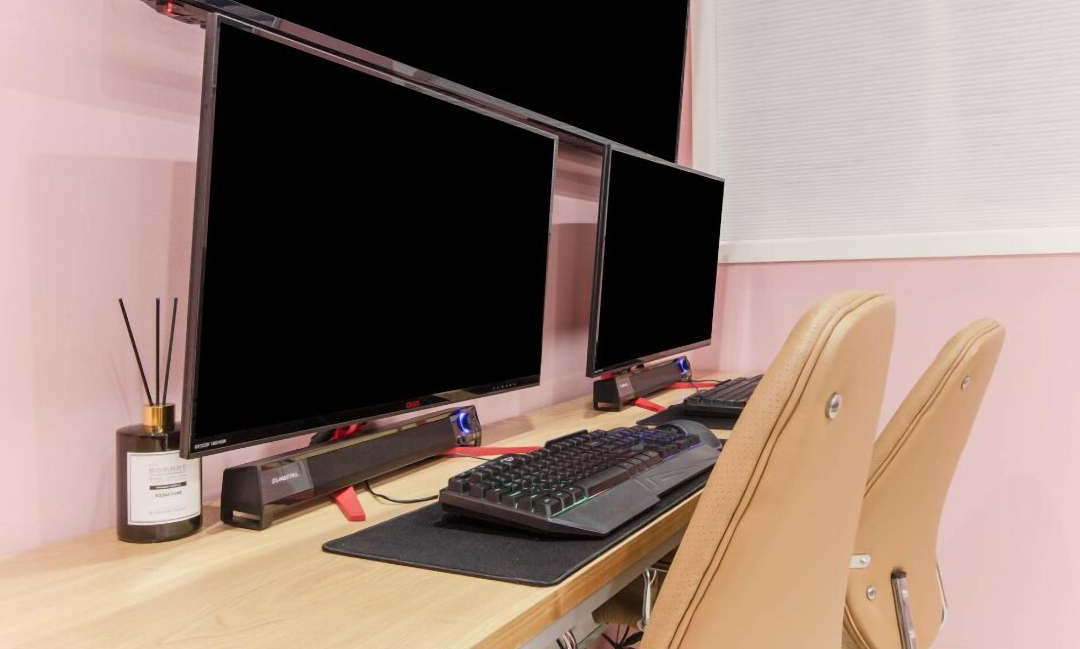 A workspace with two monitors, a keyboard, and a chair.